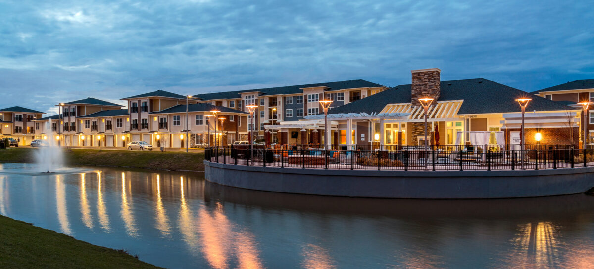 Photo at dusk of a multifamily property with a pond in the front