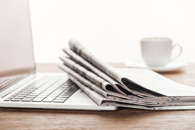 stack of newspapers laid upon a laptop keyboard