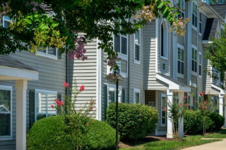 Exterior photo of a multifamily building with lush green bushes and trees