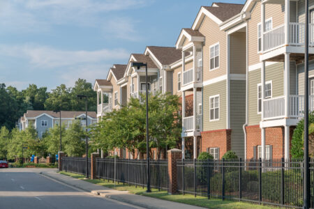 Exterior photo of a multifamily building with a brick and iron fence