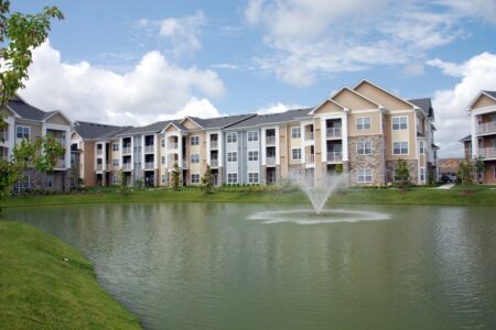 Photo of a pond with a fountain and a multifamily building in the background